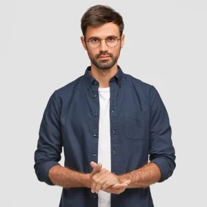 waist-up-portrait-handsome-serious-unshaven-male-keeps-hands-together-dressed-dark-blue-shirt-has-talk-with-interlocutor-stands-against-white-wall-self-confident-man-freelancer waist-up-portrait-handsome-serious-unshaven-male-keeps-hands-together-dressed-dark-blue-shirt-has-talk-with-interlocutor-stands-against-white-wall-self-confident-man-freelancer